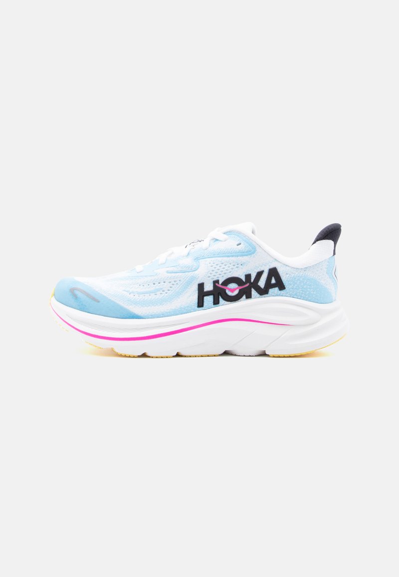 Lys blå og hvit treningssko med tykk hvit såle, rosa stripe, svart hælflik og svart "HOKA"-logo på siden.
