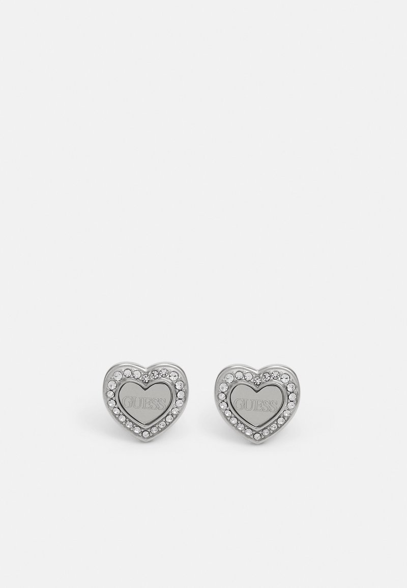 Silver heart-shaped stud earrings featuring a center with the engraved brand name and surrounded by small clear gemstones.