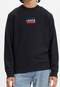 Svart sweatshirt med rund halsringning, prydd med en rektangulär Levi's-logotyp i blått, vitt och rött på framsidan. Mjuk textur och ribbade muddar.