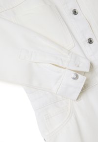 Giacca in denim bianco con bottoni a pressione, tasche frontali e dettagli sui polsini. Tessuto texturizzato con un design pulito e strutturato.