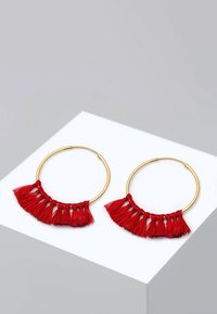 Goldene Creolen mit einem roten Quasten-Design am Boden, mit mehreren Strängen, die einen geschichteten, fransigen Effekt erzeugen.