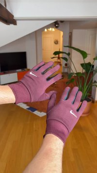 Bordó kesztyű szoros illeszkedéssel, fehér Nike logóval és fekete részletekkel az ujjvégeken. Rugalmas anyag texturált felülettel.