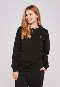 Zwarte katoenen sweatshirt met lange mouwen, ronde hals en geribbelde manchetten. Heeft een klein geborduurd logo op de borst. Zachte textuur.