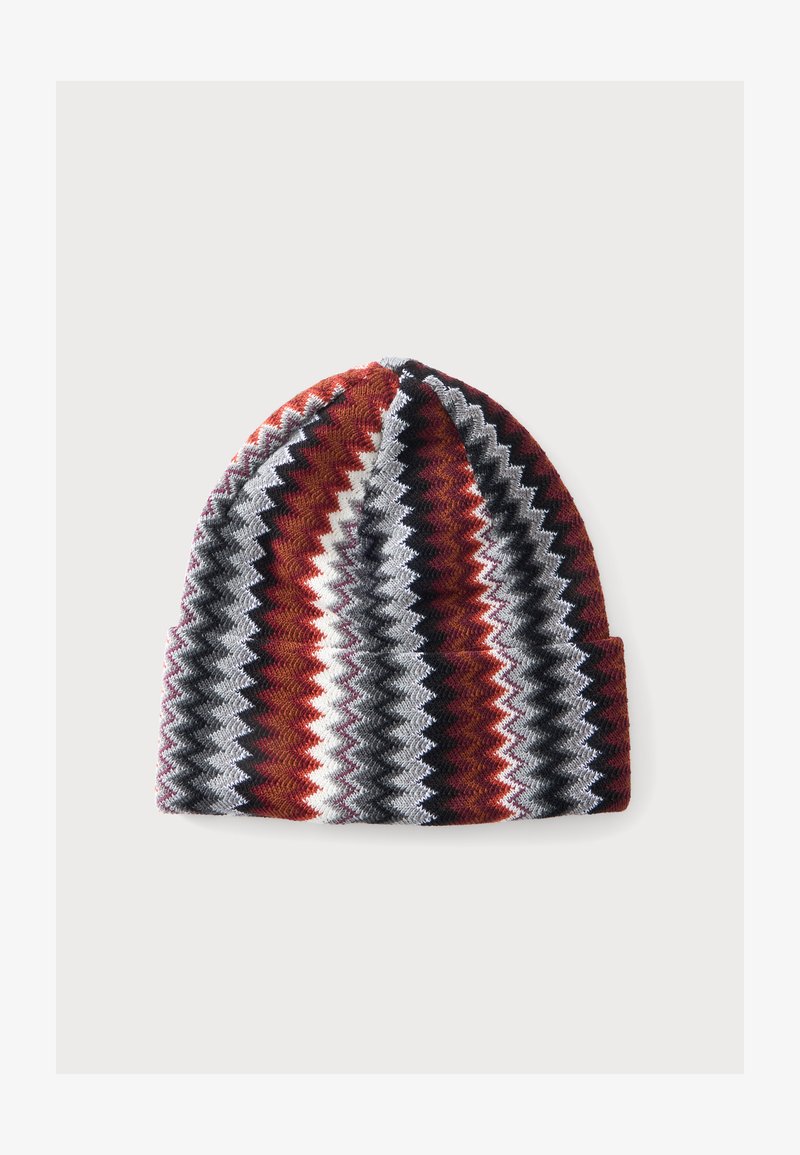 Bonnet tricoté avec des rayures en zigzag rouges, noires, blanches et grises sur un fond clair uni.