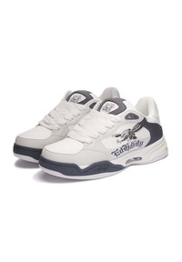 Zapatillas de cuero blanco con acentos grises, con una suela texturizada, un logo prominente en el lateral y un diseño de cordones.