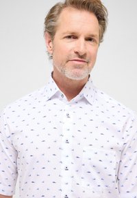 Korte mouwen witte shirt met een blauw patroon van kleine boten, voorzien van een knoopsluiting en een zak aan de linkerkant.