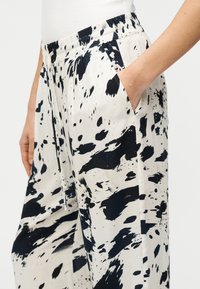 Μαύρο και άσπρο παντελόνι με μοτίβο, κατασκευασμένο από ελαφρύ ύφασμα, με ελαστική μέση και πλαϊνές τσέπες, σε άνετη, φαρδιά γραμμή.