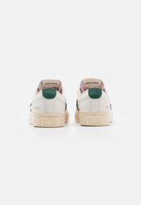 Zapatillas de cuero blancas con acentos verdes, paneles traseros texturizados y diseño minimalista. Cuentan con suelas de goma y un logotipo en la parte trasera.