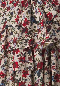 Blomsterkjole med lagdelte flæser. Lyst beige stof med røde, blå og grønne blomsterprint. Blød tekstur, afslappet design.