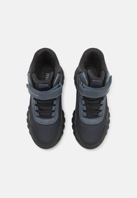 Zapatillas deportivas azul marino con una parte superior de malla texturizada, suela de goma y correa ajustable de Velcro. Presenta acentos reforzados y cordones.