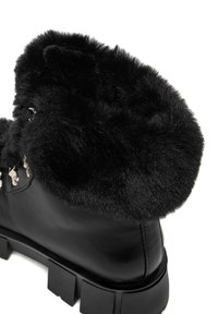 Černé kožené kotníkové boty s límcem z umělé kožešiny, mají silnou texturovanou podrážku a kovové očka na šněrování.