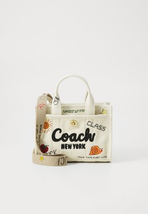 Sac fourre-tout en toile avec le logo « Coach New York », des griffonnages colorés, et une sangle ajustable beige avec des détails d'étoiles et de texte.