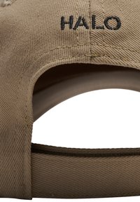 Beżowa czapka bejsbolowa z materiału z czarnym haftowanym napisem "HALO" nad otworem na regulowany pasek z tyłu.