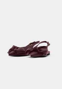 Burgundi színű slingback lapos cipők sima anyagból, oversize masni díszítéssel az orrán és kicsi csattal a bokapánton.