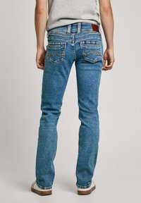 Svetlo modri kavbojki s slim fit krojem, ki imajo visok pas, svetlo rjavo usnjeno oznako in okrasno šivanje na zadnjih žepih.