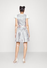 Silbernes Satin-Kleid mit spitzenbesetzten Ärmeln, tailliertem Gürtel und plissiertem Rock. Das Kleid hat einen dezenten Glanz und pinke Akzentierungen.