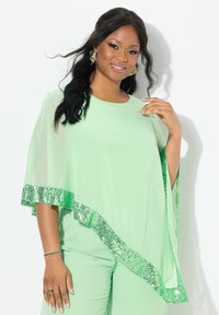 Top trasparente verde menta con un design fluido, caratterizzato da un orlo a scallop decorato con accenti di paillettes verdi. Tessuto leggero, vestibilità comoda.
