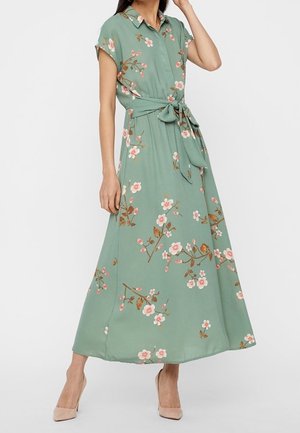 Blomstret maxi kjole i blødt grønt stof med krave, korte ærmer, taljebælte og pink blomster mønster over hele kjolen.