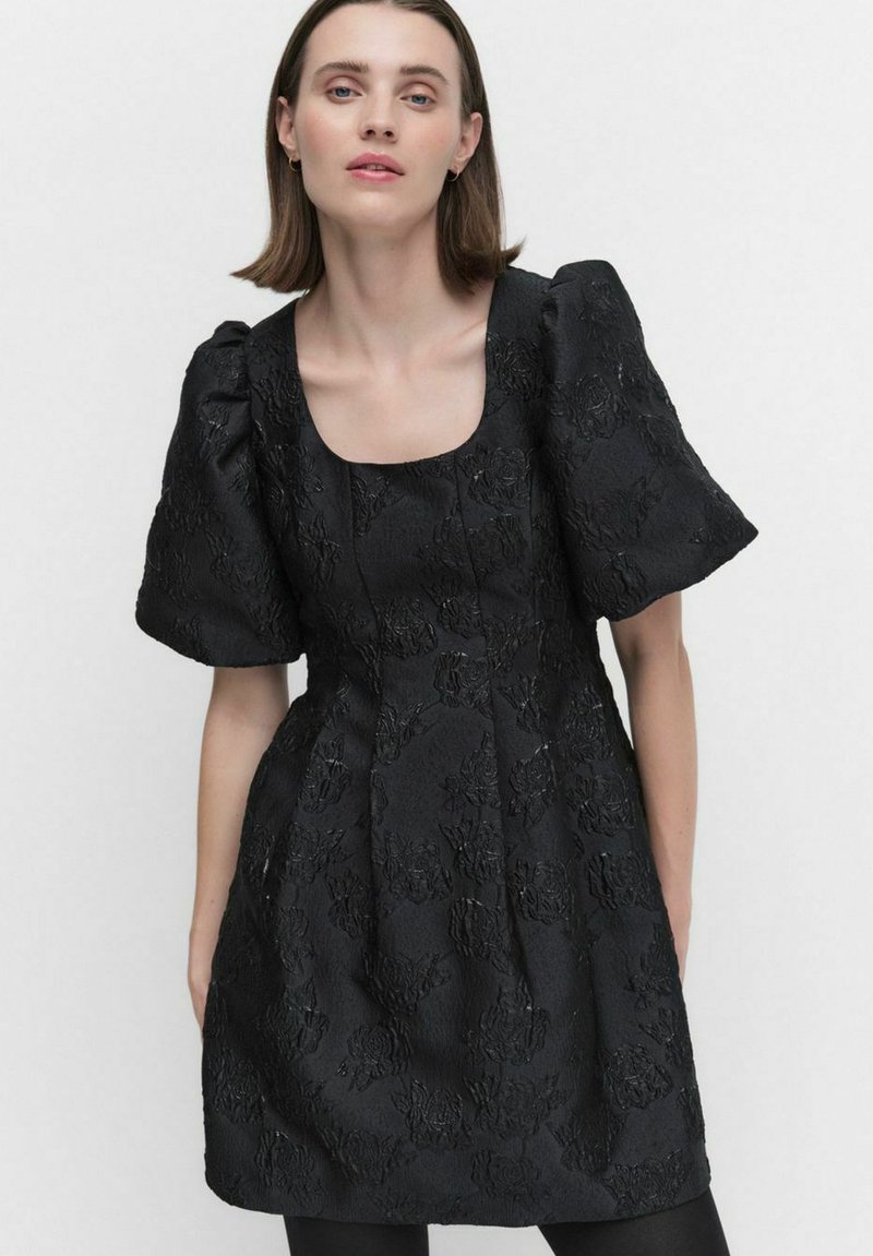 Svart klänning med ett strukturerat blomster mönster, korta puffärmar, fyrkantig halsringning och en figurnära överdel med en utsvängd kjol.