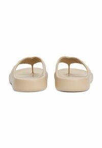 Beige slip-on sko med åben hæl og udskæringsdesign. Glat tekstur, minimalistisk form, flade såler og ingen synlig hardware.