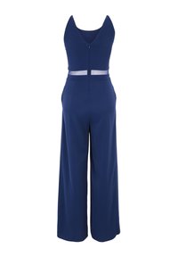 Marinblå jumpsuit i mjukt tyg, med djup V-rygg, genomskinligt midjeinlägg och vida ben. Dragkedjestängning bak.