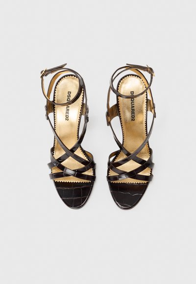Black leather high-heeled sandals with crisscross straps and a gold insole. Patterned texture mimics crocodile leather. Buckle closure design.