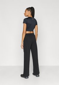 Μαύρο κοντό t-shirt με κοντά μανίκια σε συνδυασμό με μαύρο φαρδύ παντελόνι φόρμας με πλαϊνές τσέπες. Λεία υφή υφάσματος.