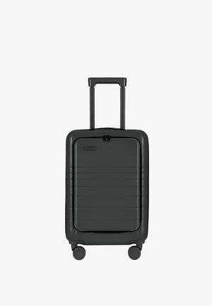 Harde zwarte koffer met horizontale ribbels, dubbele wielen en een uitschuifbaar handvat. Voorzien van een ritssluiting en duurzaam materiaal.