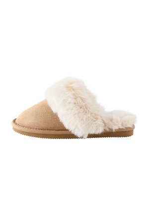 Pantoufle beige unique avec une doublure blanche douce et duveteuse et un dos ouvert, conçue pour un usage intérieur avec une semelle plate et texturée.