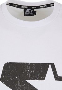 White cotton t-shirt with a black distressed star logo at the front. Crew neck with a black label featuring brand text on the collar.