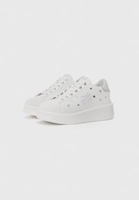 Adidași platformă albi cu o textură netedă, având detalii decorative din cristale, ochiuri argintii și un design de talpă cu marcă.