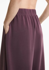 Lila, lätta tygbyxor med elastisk midja, med sidofickor och en len yta. Enkel, minimalistisk design.
