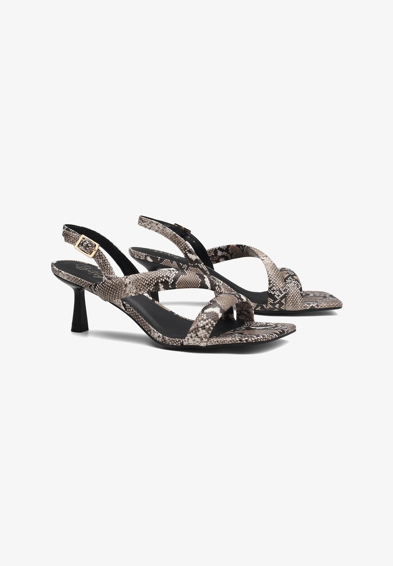 Sandalias de tacón alto en estampado de serpiente negro y beige con correas cruzadas, un tacón delgado y una superficie texturizada. Correa en el tobillo ajustable con herrajes dorados.