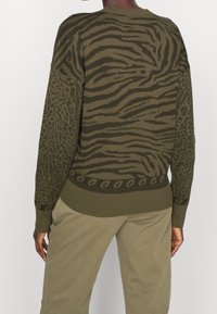 Maglione verde lavorato a maglia con un mix di strisce tigre e stampa leopardo, con orlo e polsini a costine. Texture morbida e vestibilità rilassata.