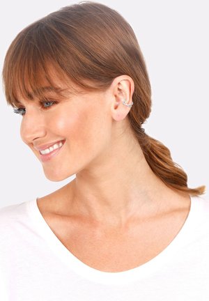 Silberner Ohrclip mit einem eleganten, geschwungenen Design, der am äußeren Ohr sitzt. Die Haare sind teilweise zurückgesteckt, wodurch das Schmuckstück deutlich sichtbar ist.