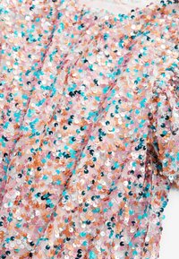 Pailletttyg i rosa, persika, silver och turkos färg, med en texturerad yta som har överlappande runda paljetter och mjuka draperingar.