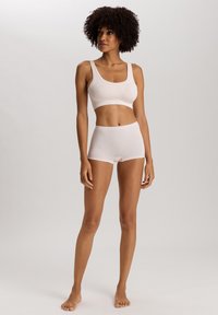 Ljusrosa trådlös bh med breda axelband och matchande hög midja-shorts. Slät, elastisk tyg med en sömlös design.
