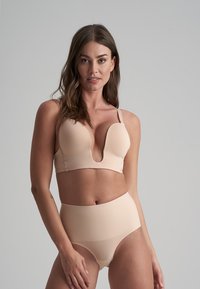 Set di lingerie color nude composto da un reggiseno morbido e liscio con scollatura a V profonda e culotte a vita alta, entrambi realizzati in materiale elasticizzabile.