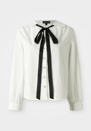 White long-sleeve blouse with a black ribbon bow at the collar and decorative buttons down the front.