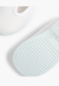 Ciorap de tip slip-on din textile albe, cu un superior texturat, vârf rotund și o talpă din cauciuc albastru deschis, cu un model nervurat.