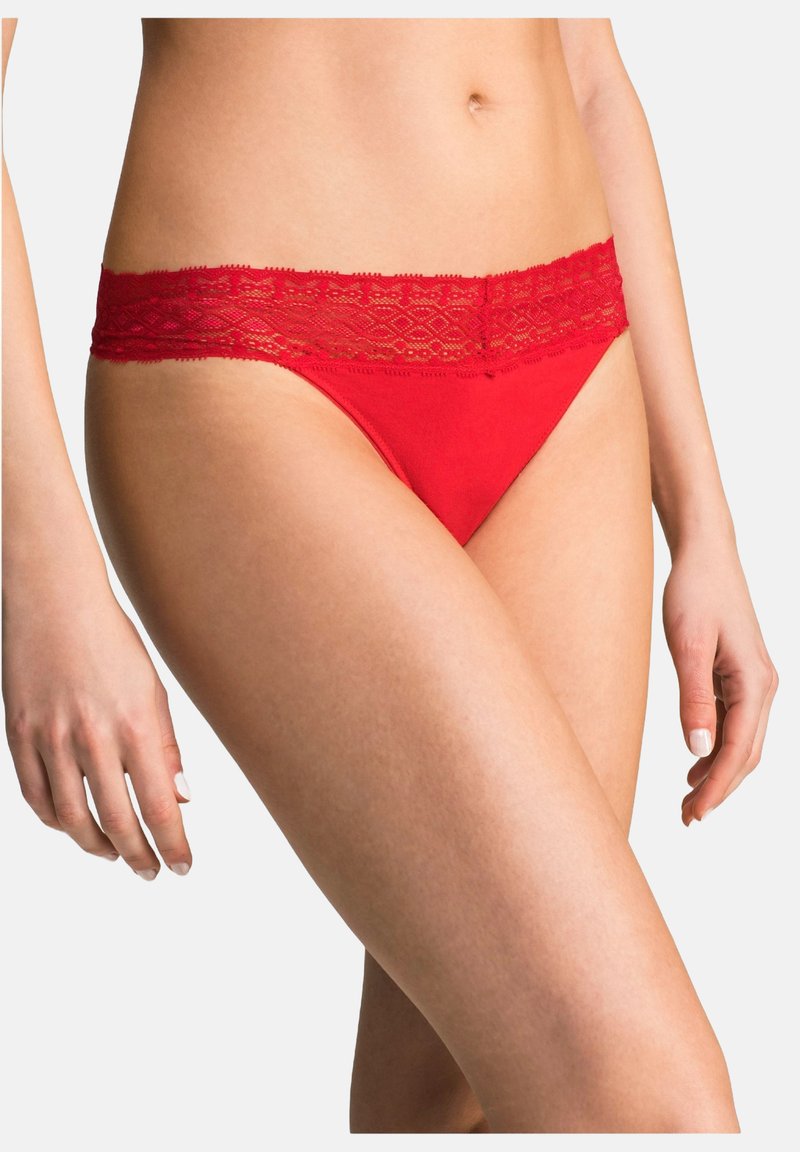 Slip rossi con una cintura in pizzo, caratterizzati da un corpo liscio e delicati dettagli in pizzo lungo il bordo superiore.