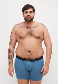 Boxer da uomo blu con elastico nero marchiato "JACK & JONES". Presenta un design aderente e una texture liscia, stile minimalista.