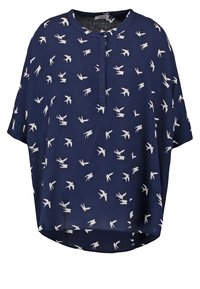 Blouse bleu marine à manches courtes, avec une encolure fendue boutonnée et des motifs d'oiseaux blancs partout. Tissu semi-transparent.