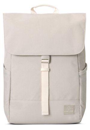 Backpack in light beige fabric with a fold-over flap, a buckle clasp, front pocket, and side pockets. Features a top handle for carrying.