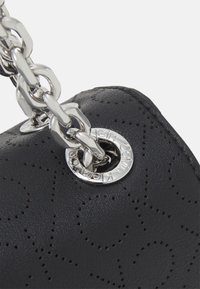 Sort lædertaske med en tekstureret overflade med perforerede mønstre, sølvfarvet hardware og en kraftig kæderem. Rund logo-detalje synlig.