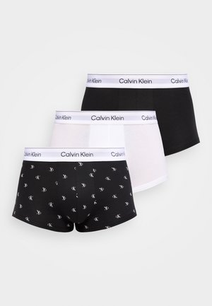 Trzy pary bokserek Calvin Klein w kolorach czarnym, białym oraz czarnym z białym wzorem logo, każda z białym paskiem w talii i brandingiem Calvin Klein.