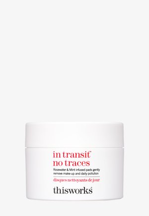 Biały, okrągły pojemnik z nakręcaną pokrywką, oznaczony napisem "w tranzycie brak śladów", z czerwonym i czarnym tekstem. Zawiera podkładki nasycone wodą różaną i miętą.