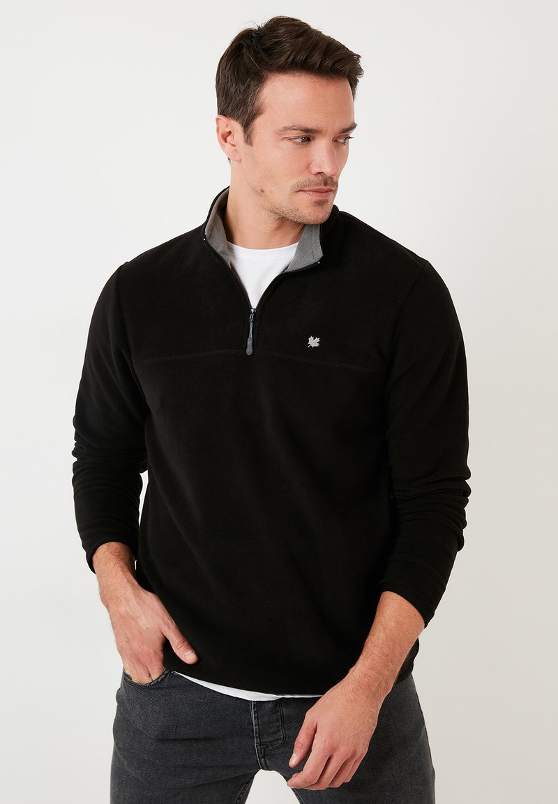 Pullover in pile nero con colletto grigio, mezza zip sul davanti, maniche lunghe e un piccolo logo sul petto. Tessuto morbido, design casual.