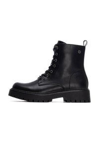 Botas de cuero negras hasta el tobillo con cordones en la parte delantera, punta redonda y suela de goma gruesa con profundas estrías. Acentuadas con una tira para facilitar el calzado.