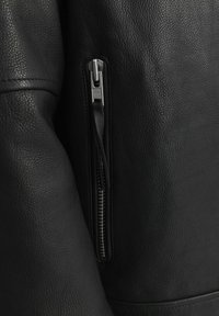 Black leather jacket featuring a textured finish, with a visible metal zipper on the sleeve and YKK branding on the zipper pull.